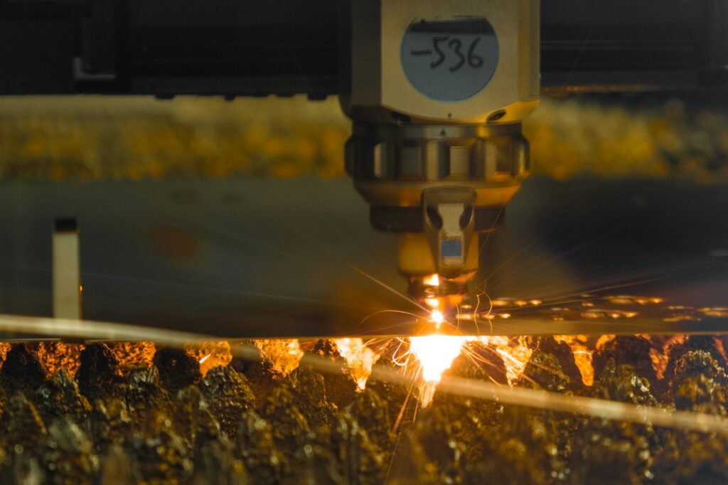 Laser cutter carves thin metal sheet with sparks in shop